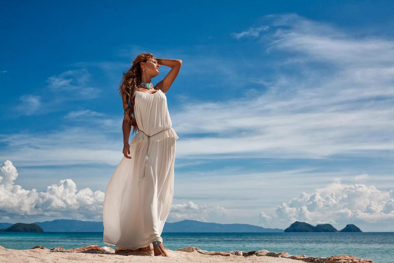 Женщина в синем платье стоит на пляже 9