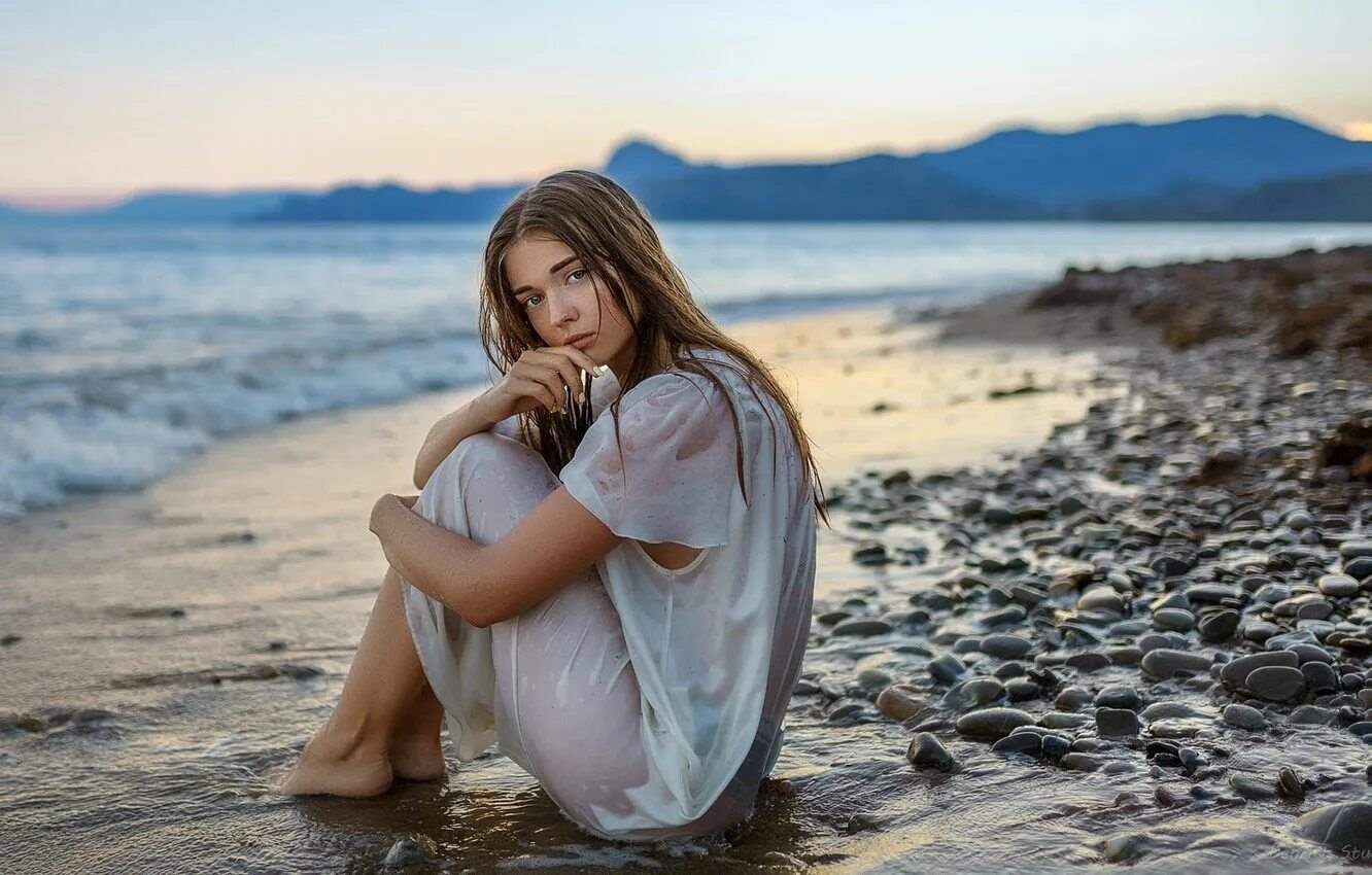 Женщина, сидящая на камне у океана 9