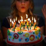 Маленькая девочка держит праздничный торт со свечами 9